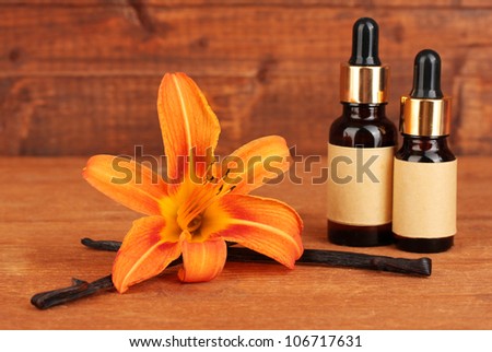 Vanilla pods with essential oil on wooden background close-up