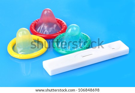 birth condoms and pregnancy test on blue background
