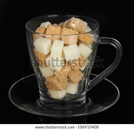 white refined sugar and Lump brown cane sugar cubes in glass cup isolated on black