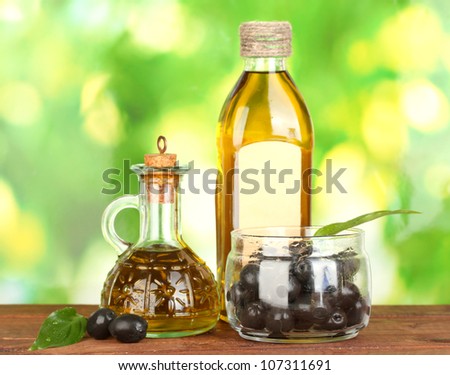 Olive oil bottle and small decanter on green background