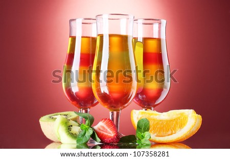 fruit jelly in glasses and fruits on red background
