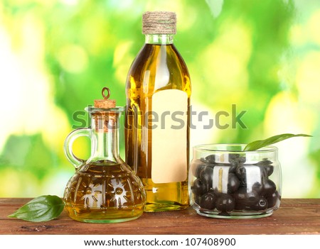 Olive oil bottle and small decanter on green background