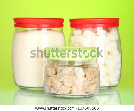 Jars with brown cane sugar lump, white crystal sugar and white lump sugar isolated on white