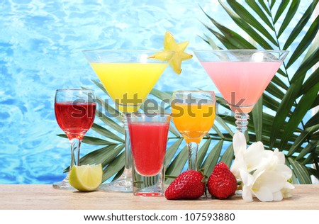 exotic cocktails and flowers on table on blue sea background