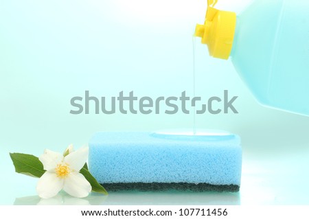bright sponge and flower  with dish washing liquid on blue background