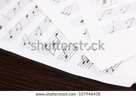 Musical notes and feather on wooden table