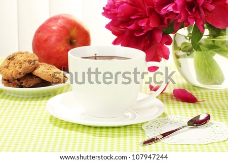 cup hot chocolate, apple, cookies and flowers on table in cafe