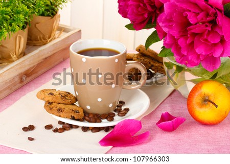 cup of coffee, cookies, apple and flowers on table in cafe