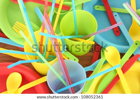 bright plastic disposable tableware on wooden background close-up