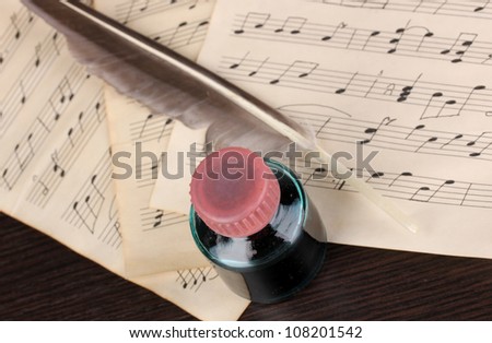 Musical notes and feather on wooden table