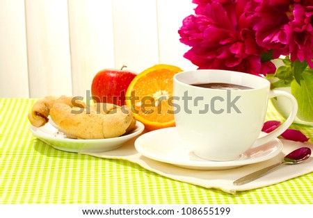 cup hot chocolate, apple, orange, cookies and flowers on table in cafe