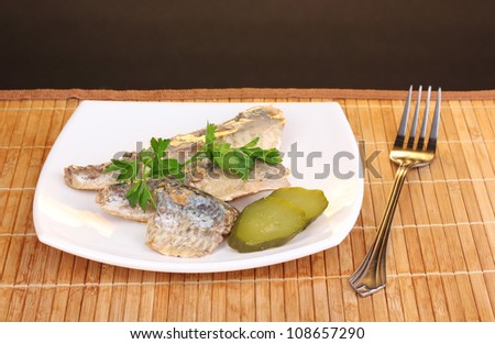Tasty mackerel on plate on wooden mat on brown background