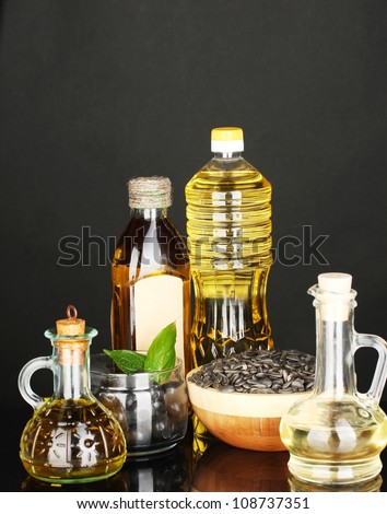 Olive and sunflower oil in the bottles and small decanters isolated on black background close-up