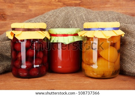 Jars with canned fruit on wooden background close-up