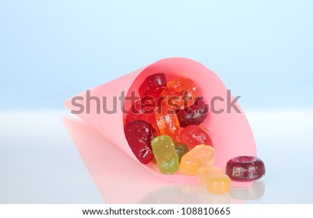 Tasty colorful candies in bright bag on blue background close-up