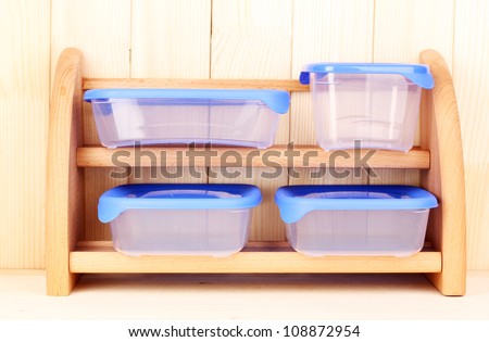 Plastic containers for food on shelf on wooden background