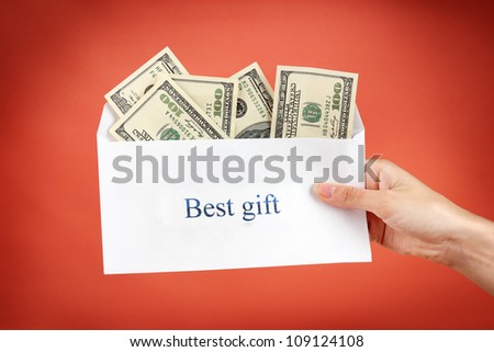 Woman\'s hand holding an envelope with money on red background