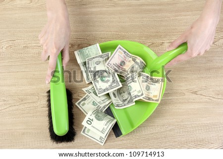 Sweeps money in the shovel on wooden background close-up