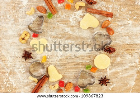 Frame made of candied fruit, nuts, unbaked biscuits and molds for cookies on a wooden table close-up