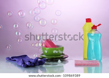 Washing dishes. Cleaning products on bright violet background