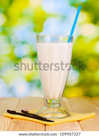 Vanilla milk shake on wooden table on bright background