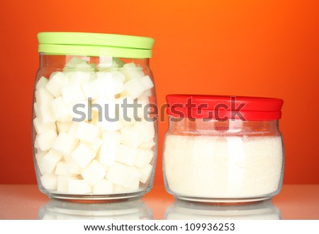 Jars with white lump sugar and white crystal sugar on colorful background