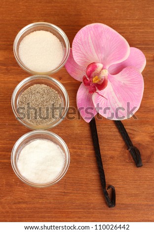 Vanilla pods, vanilla, vanilla sugar and vanilla essence on wooden background close-up