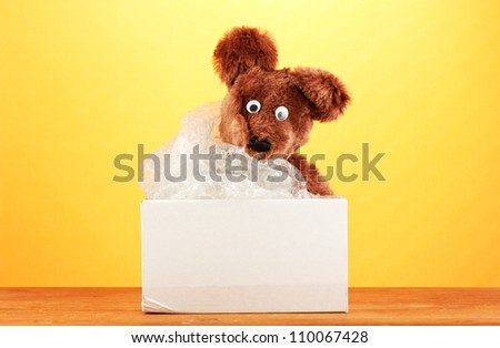 Opened parcel with a child's toy on yellow background close-up
