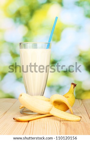 Banana milk shake on wooden table on bright background