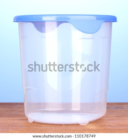Plastic container for food on wooden table on blue background