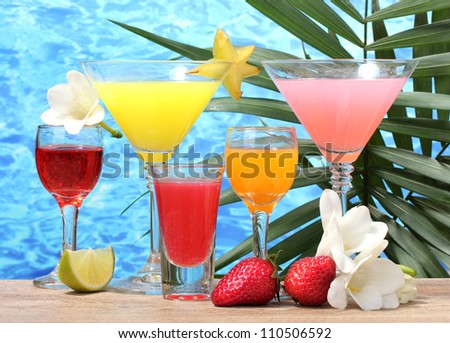exotic cocktails and flowers on table on blue sea background