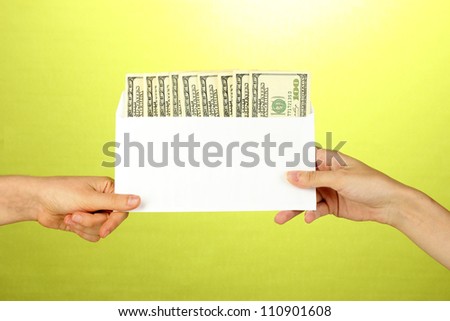 Woman\'s hand passes the envelope with the salary on green background