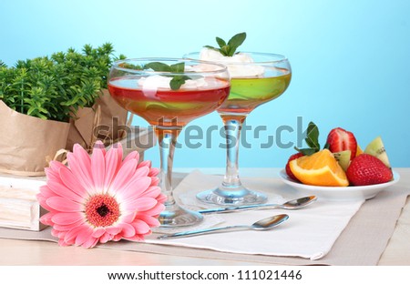 fruit jelly in glasses and fruits on table on blue background