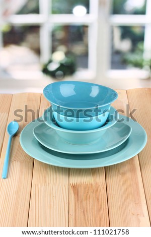 Blue tableware on wooden table on window background