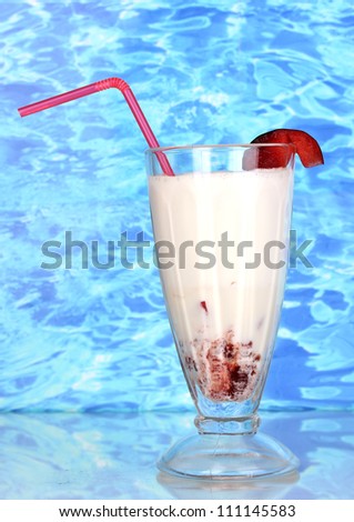 Delicious milk shake with fruit on table on blue sea background