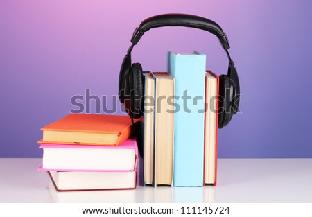Headphones on books on purple background