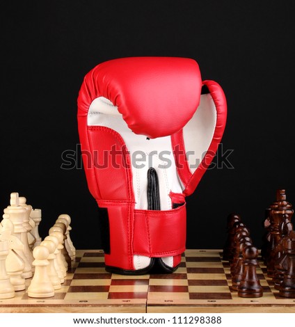 Chess board and boxing glove isolated on black