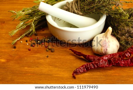 dried herbs in mortar and  vegetables, on wooden background