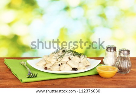 Delicious cooked dumplings in the dish on bright green background