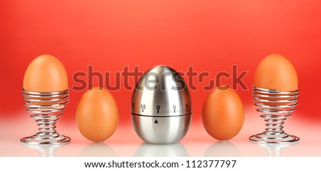 egg timer and eggs on red background