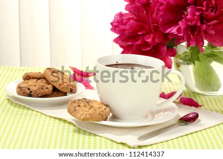 cup hot chocolate, cookies  and flowers on table in cafe