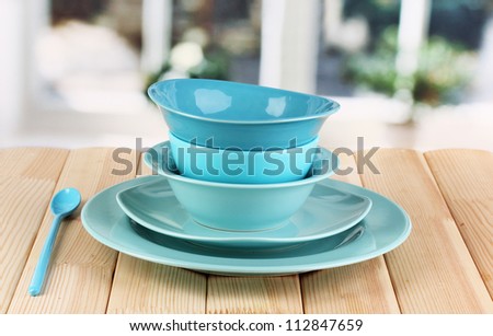 Blue tableware on wooden table on window background