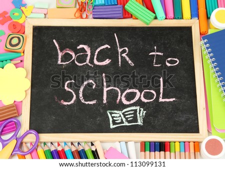 The words 'Back to School' written in chalk on the small school desk with various school supplies close-up