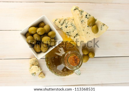 Cheese with mold and decanter of olive oil on white wooden background close-up