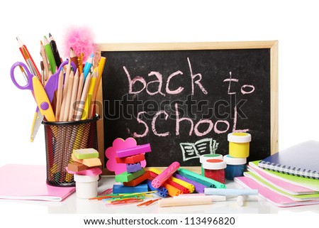 The words \'Back to School\' written in chalk on the small school desk with various school supplies close-up isolated on white
