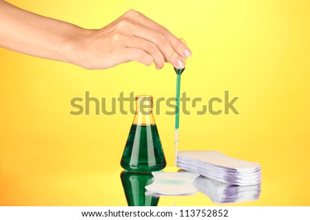 Testing sanitary pads for absorbency, on yellow background close-up