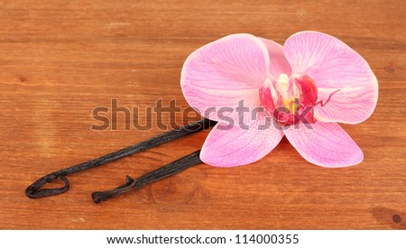 Vanilla pods with flower on wooden background
