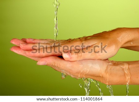 Washing hands on green background close-up