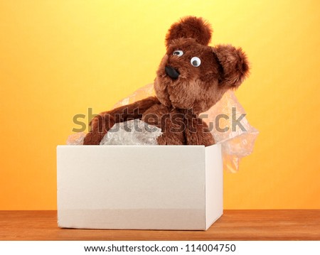 Opened parcel with a child\'s toy on yellow background close-up