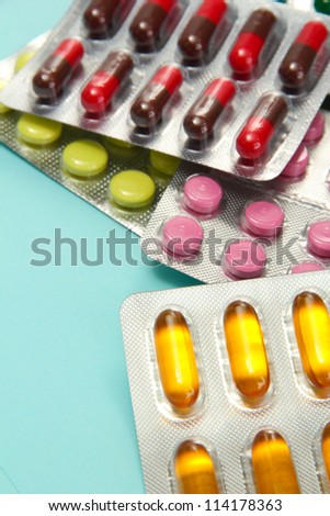 Capsules and pills packed in blisters, on blue background